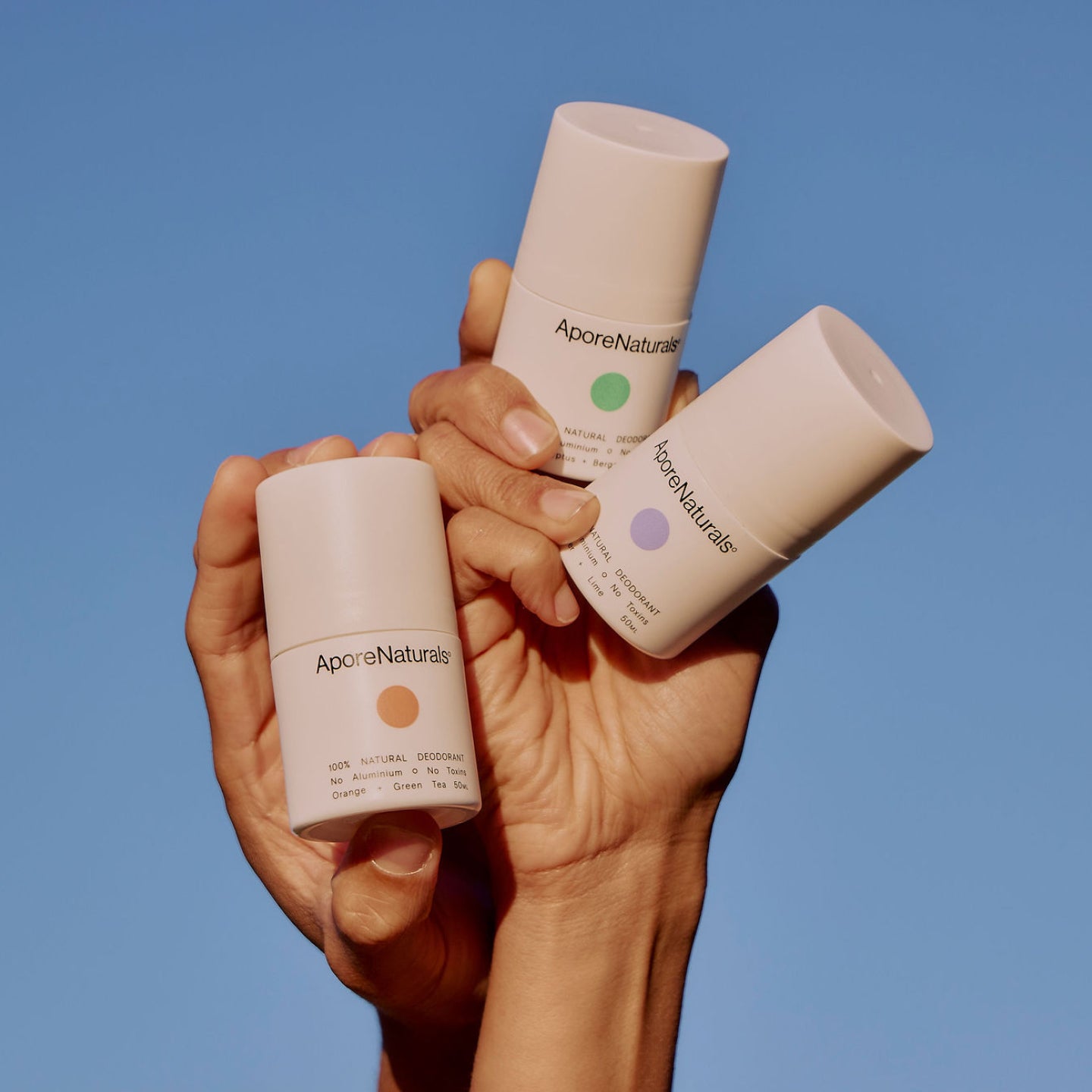 hands holding 3 variants of AporeNaturals all natural deodorants